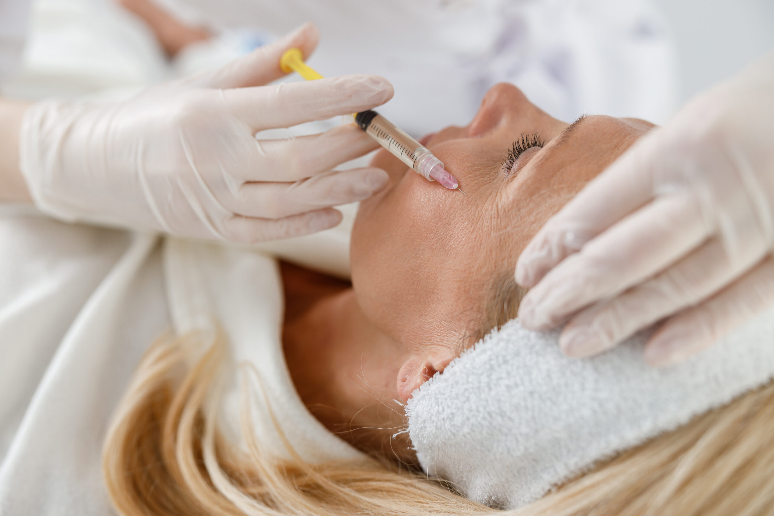 Close up treatment of a senior woman by a beautician for tightening and smoothing wrinkles on the face skin